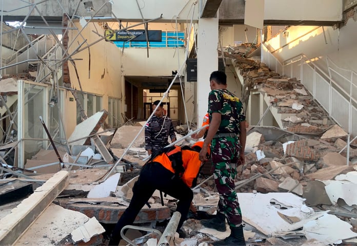 Rescue workers search through earthquake rubble on Flores Island Indonesia after 7.7 magnitude quake
