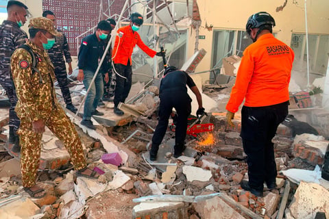 Rescuers working amid rubble of damaged building after earthquake in Maumere East Nusa Tenggara Indonesia