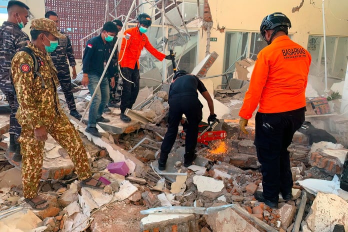 Rescuers working amid rubble of damaged building after earthquake in Maumere East Nusa Tenggara Indonesia