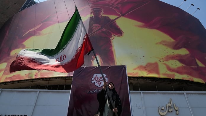 An Iranian woman waves a national flag in downtown Tehran on August 1, 2026, as the Iran-Israel war continued