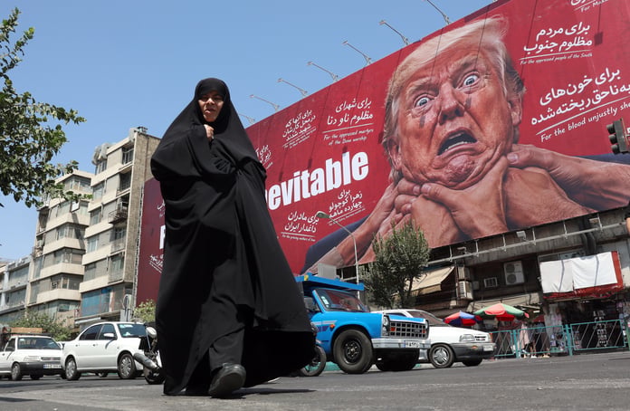 Iranian women walk past anti-US billboard in Tehran as Iran-US war sanctions escalate August 2026