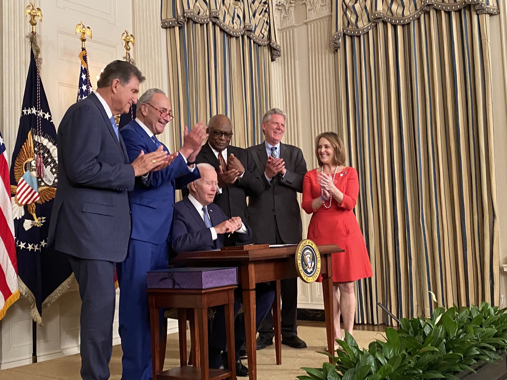 Joe Biden signing the Inflation Reduction Act at the White House in August 2022 as members of Congress applaud