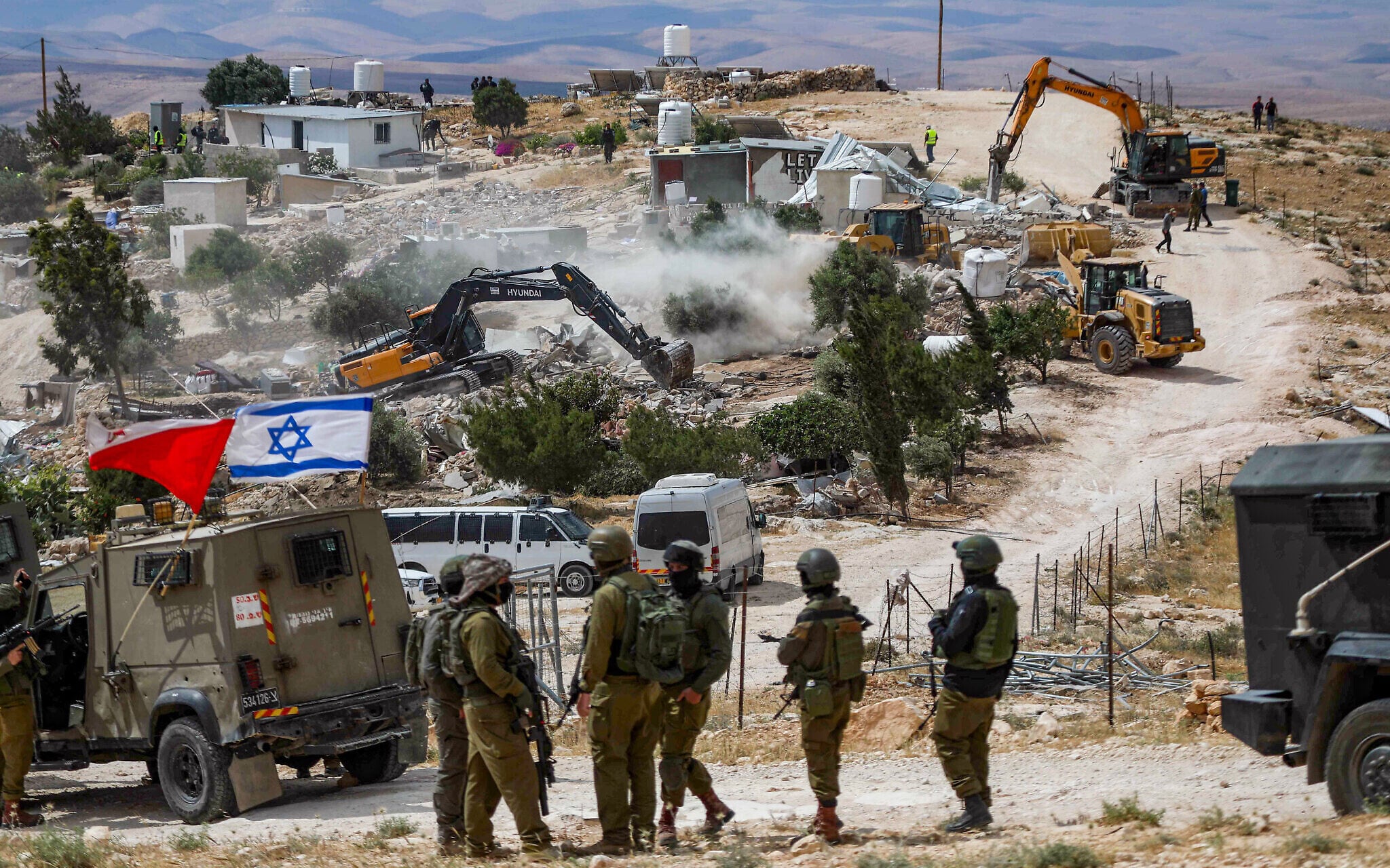 Israeli soldiers stand guard while bulldozers demolish Palestinian structures in Ed-Daba village Masafer Yatta West Bank south of Hebron May 2025