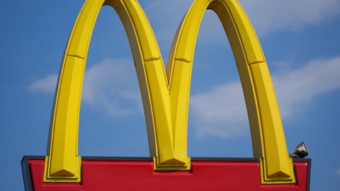 McDonald's golden arches sign against a blue sky, representing the chain's Q2 2026 earnings report showing slowing US same-store sales and a new US president appointment