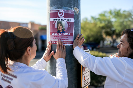 Volunteers place a Nancy Guthrie missing poster near her Tucson, Arizona home in February 2026