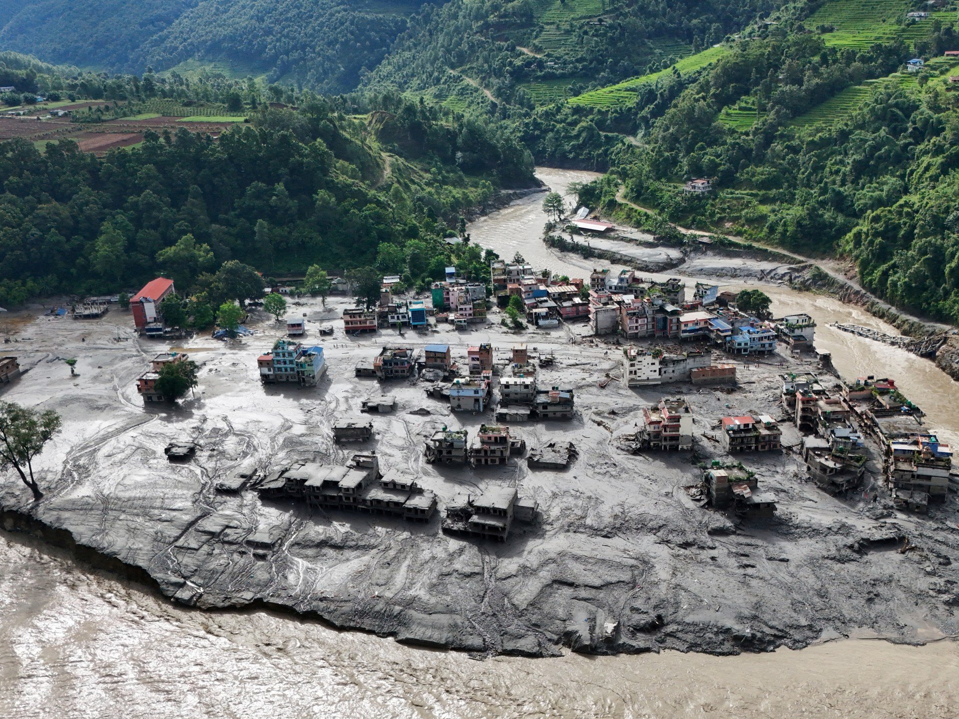 Rescue teams and survivors along a flooded river valley in Nepal's Rasuwa district following the glacial collapse disaster, August 2026