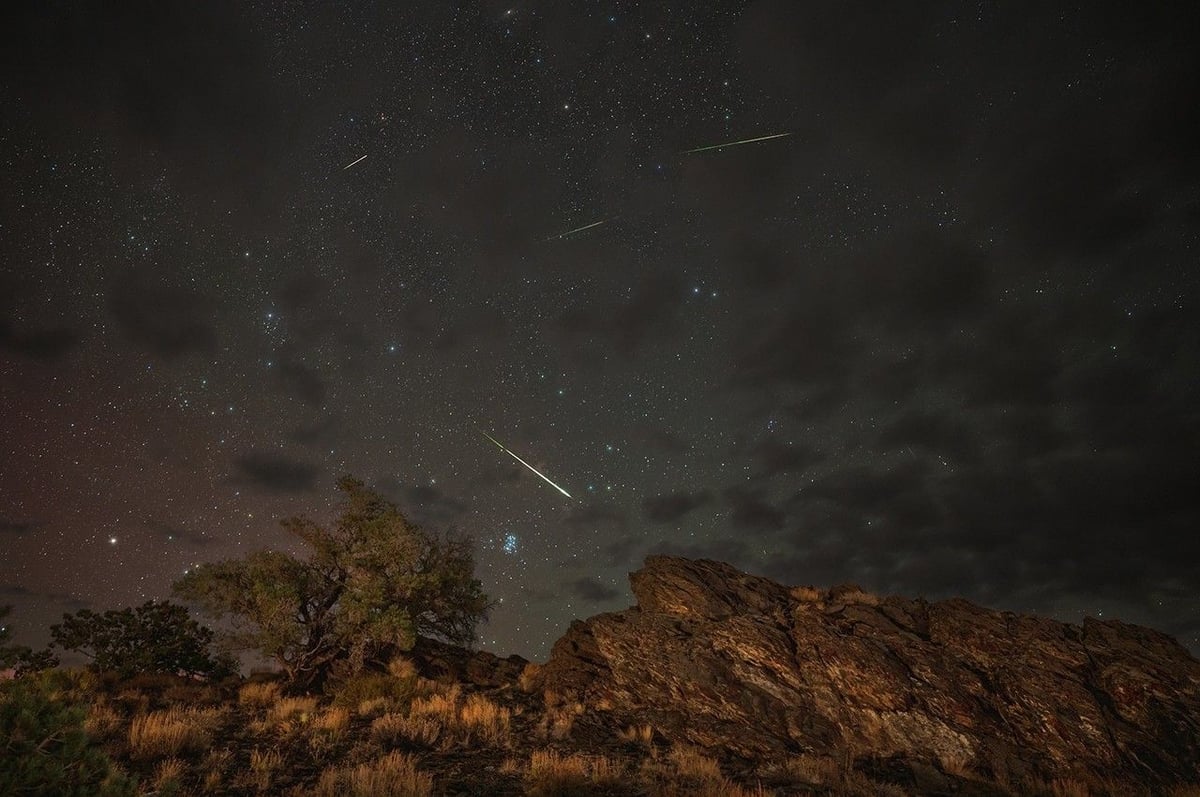 Perseid meteors streaking across the night sky above Inyo National Forest California with aurora glow visible