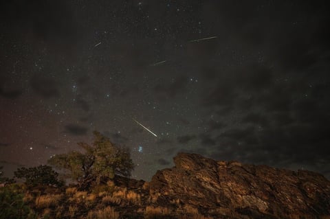 Perseid meteors streaking across the night sky above Inyo National Forest California with aurora glow visible