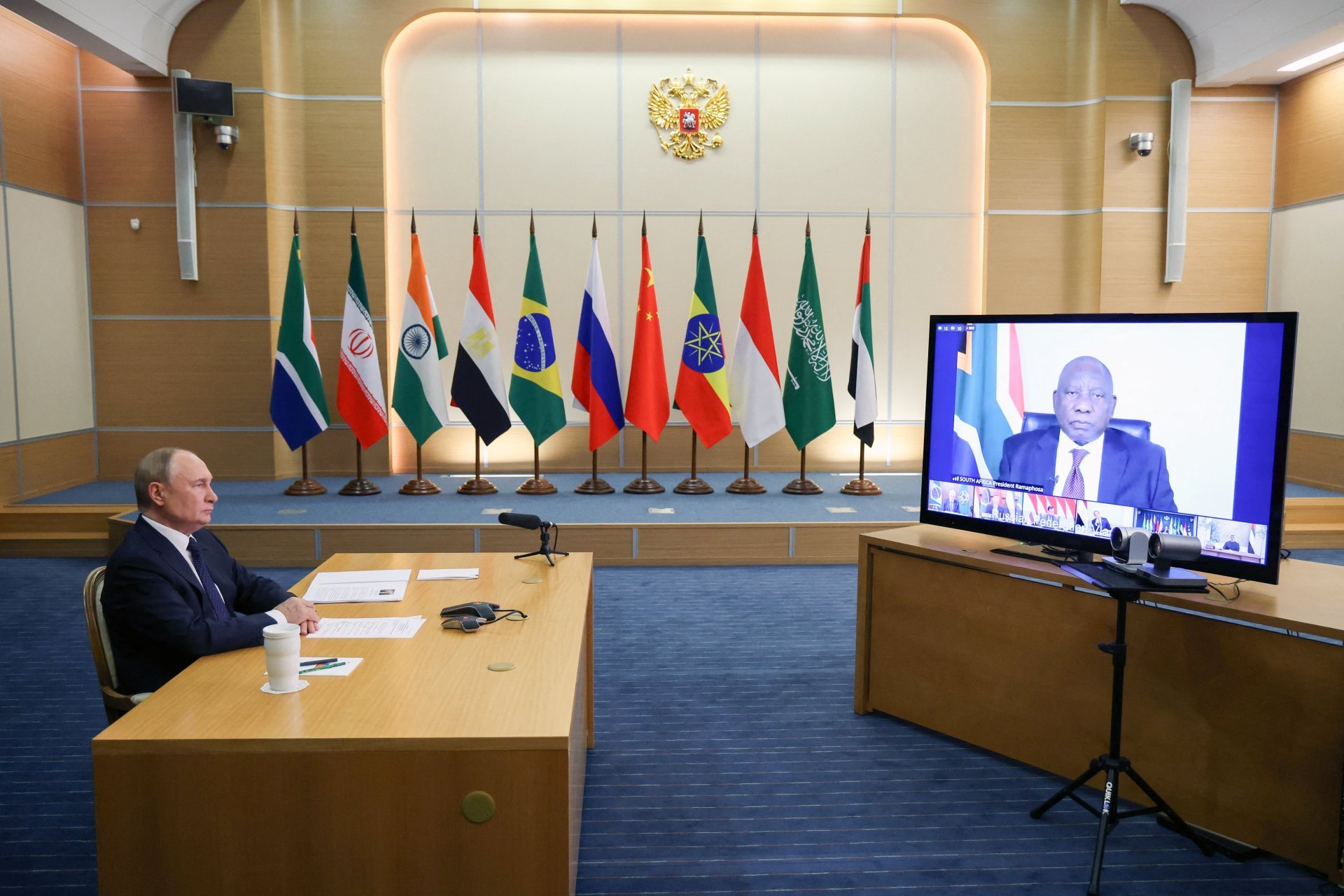 Vladimir Putin seated before a row of BRICS member flags during an online meeting of BRICS leaders