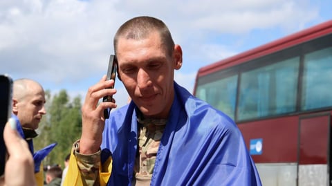 A freed Ukrainian serviceman wrapped in a national flag makes a phone call after the August 19 prisoner exchange