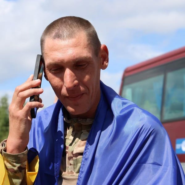 A freed Ukrainian serviceman wrapped in a national flag makes a phone call after the August 19 prisoner exchange