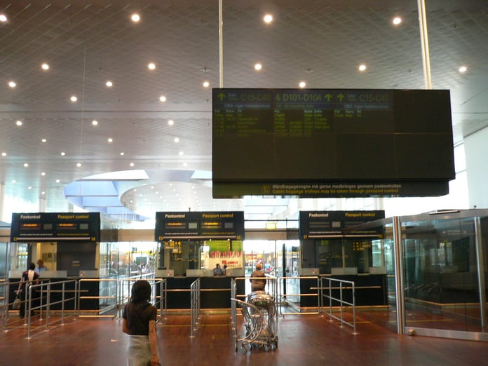 Passengers at border control booths in a Schengen airport terminal