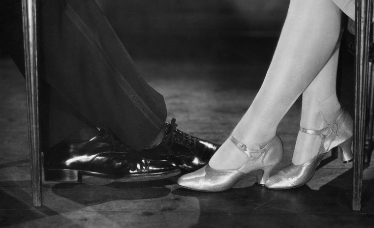 Couple playing footsie under a table illustrating intimate connection in relationships