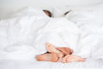Couple's feet in bed illustrating research on sex frequency and relationship happiness
