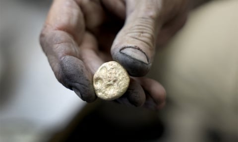 A metalworker's blackened hand holding a small freshly cast button of precious metal, illustrating the silver rate today at Rs 2,60,000 a kilogram