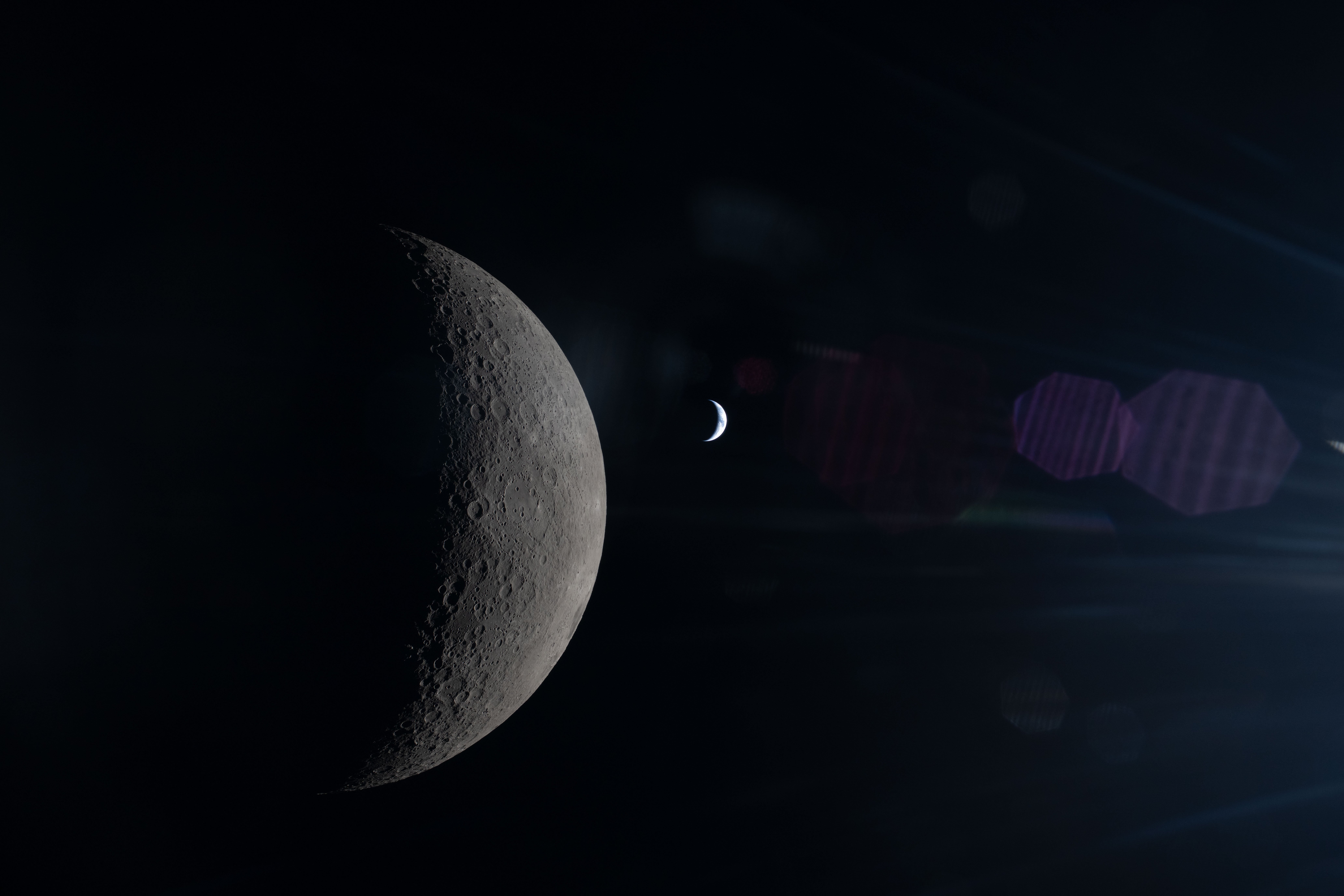 The Moon in sharp detail in the foreground with Earth small and softly lit in the background, both partially illuminated by the Sun