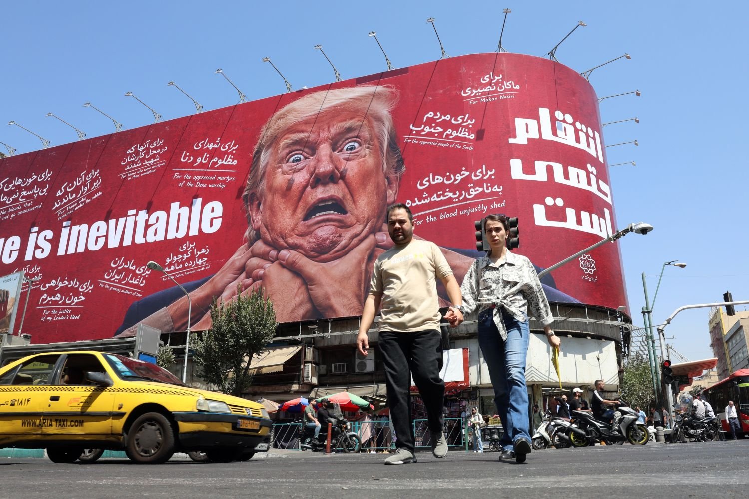 Iranians walk in front of an anti-Trump billboard in Tehran as Washington escalates its sanctions campaign