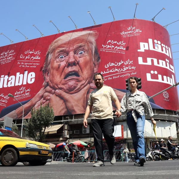 Iranians walk in front of an anti-Trump billboard in Tehran as Washington escalates its sanctions campaign