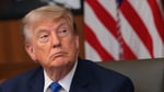 US President Donald Trump seated with American flag in background