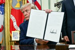 President Donald Trump holding a signed executive order in the Oval Office August 2026