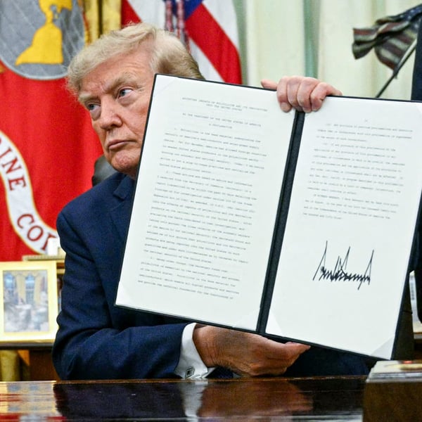 President Donald Trump holding a signed executive order in the Oval Office August 2026