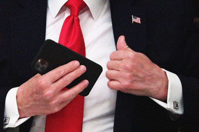 President Donald Trump on his phone posting to Truth Social, the platform whose paid API Senator Padilla's bill would target