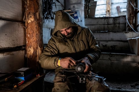 Ukrainian serviceman attaching a shell to a first-person-view drone in a dugout