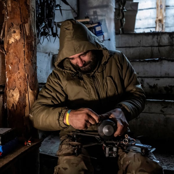 Ukrainian serviceman attaching a shell to a first-person-view drone in a dugout