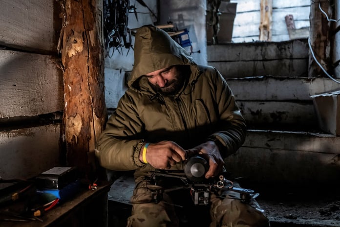 Ukrainian serviceman attaching a shell to a first-person-view drone in a dugout