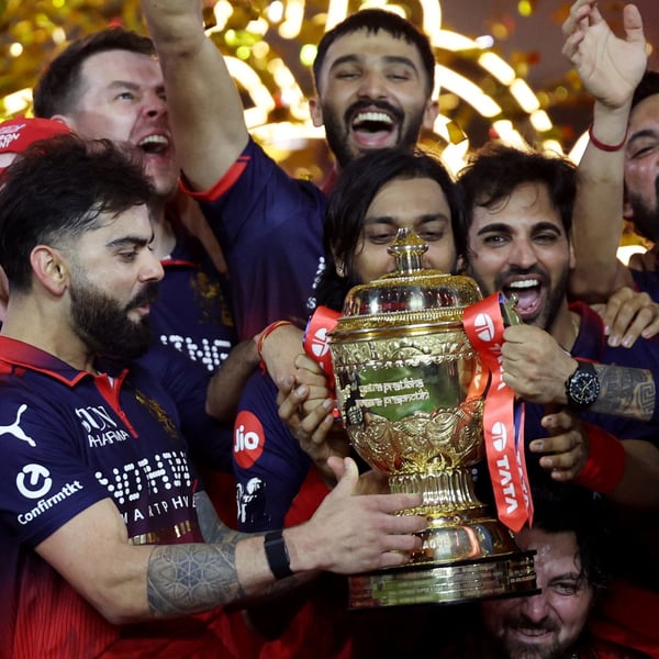 Virat Kohli holds the IPL trophy as Royal Challengers Bengaluru teammates celebrate after the 2026 final in Ahmedabad