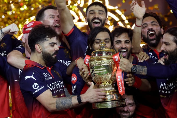 Virat Kohli holds the IPL trophy as Royal Challengers Bengaluru teammates celebrate after the 2026 final in Ahmedabad