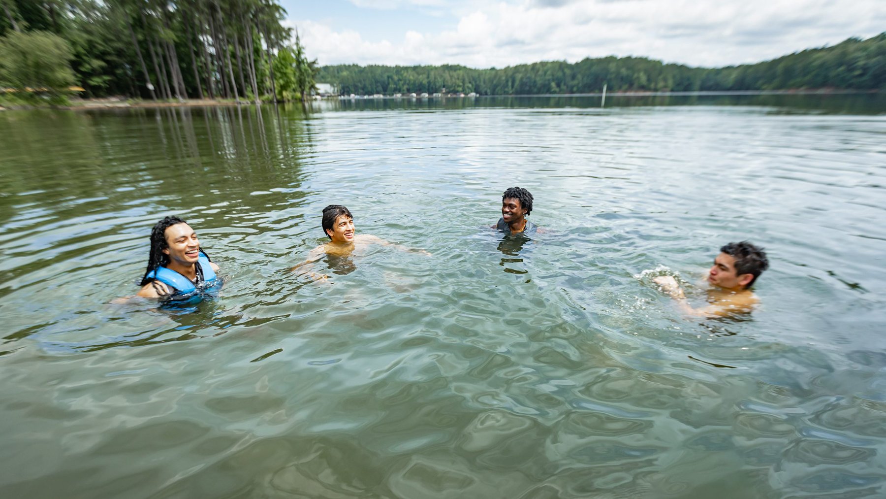 Young swimmers wearing life jackets at a lake demonstrating water safety practices recommended by the CDC