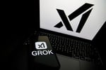 Grok logo displayed on a smartphone next to a laptop showing the xAI logo