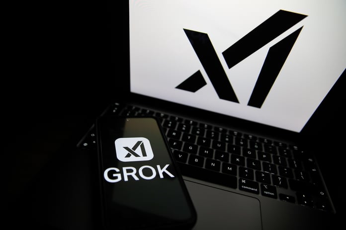Grok logo displayed on a smartphone next to a laptop showing the xAI logo