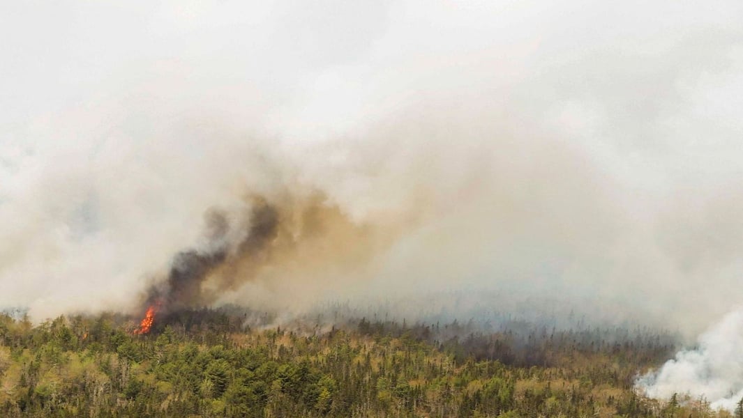 Aerial view of Canadian forest fire with flames and smoke rising through boreal forest