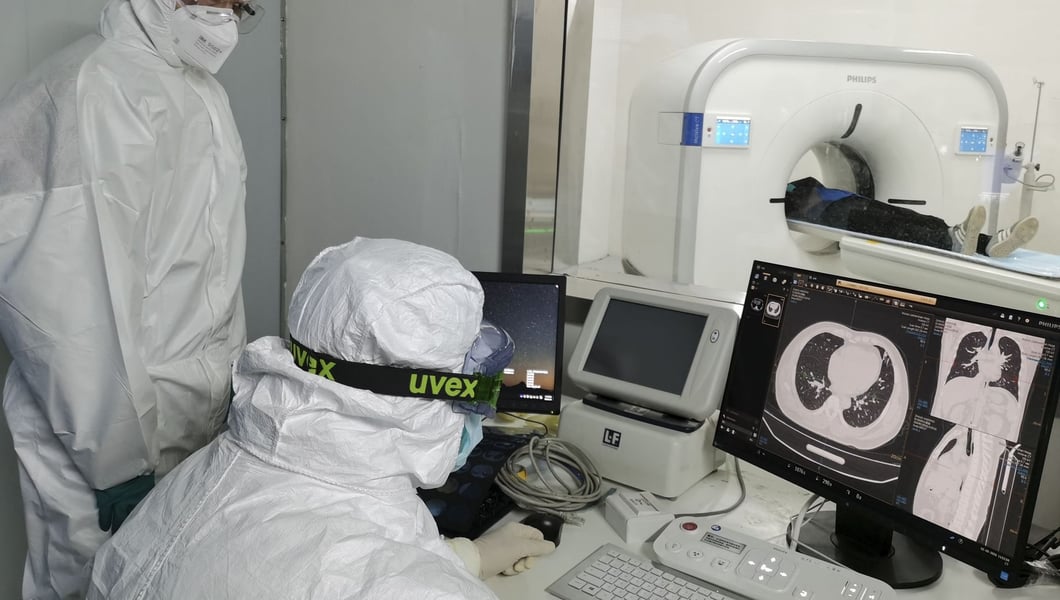 Medical staff in protective gear examine lung CT scans at a temporary coronavirus hospital in Wuhan as COVID-19 deaths mounted globally