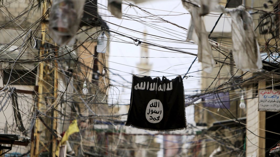 An Islamic State flag hangs amid electric wires over a street in Raqqa Syria