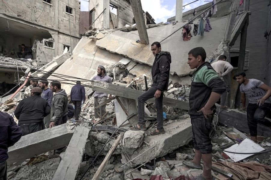 Palestinians inspect a destroyed building in Deir al-Balah