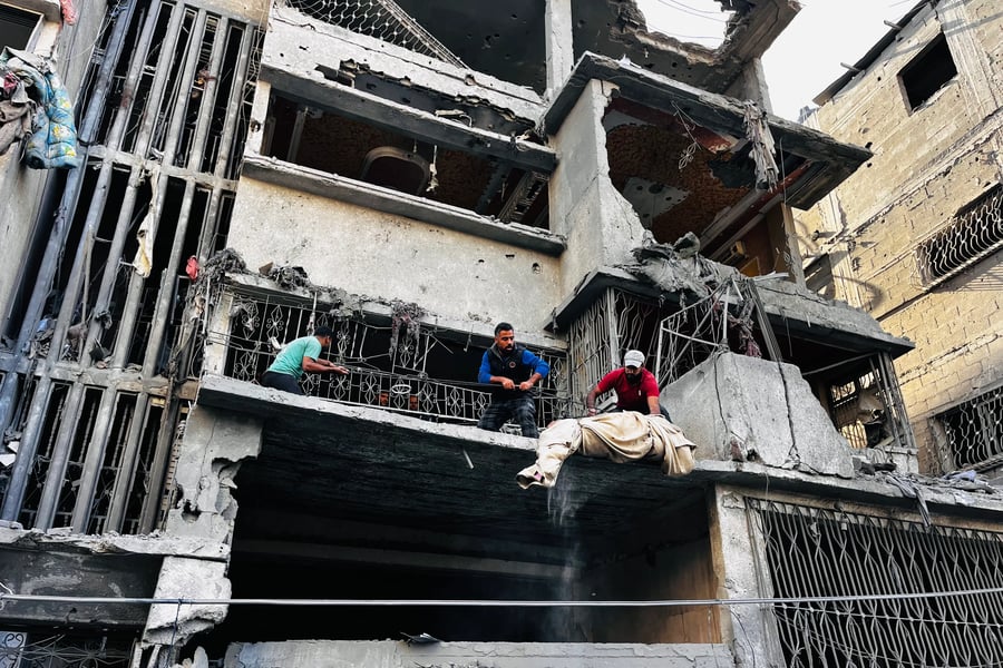 Palestinians remove a body from the rubble of a building following an Israeli strike in Beit Lahiya, Gaza