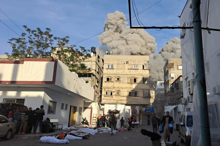 Palestinians running for shelter next to covered bodies after an Israeli air raid near the Kamal Adwan Hospital in Beit Lahia in the northern Gaza Strip
