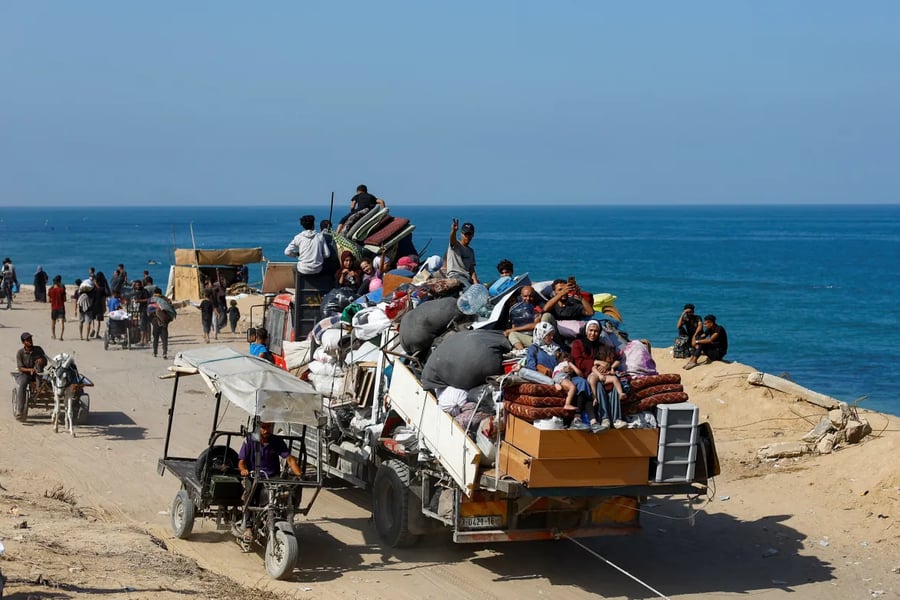 Displaced Palestinian families evacuate along Salah al-Din road carrying bags and children