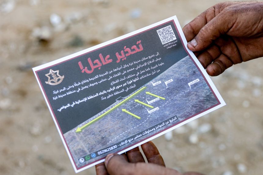 Gaza City residents collect evacuation leaflets dropped from the air