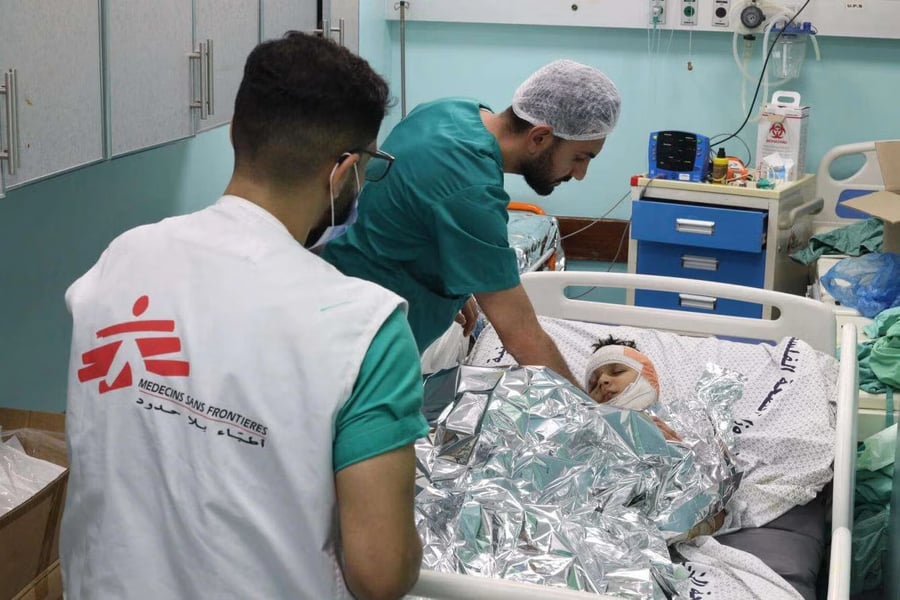 MSF nurses treat wounded patients in a crowded Gaza hospital corridor.