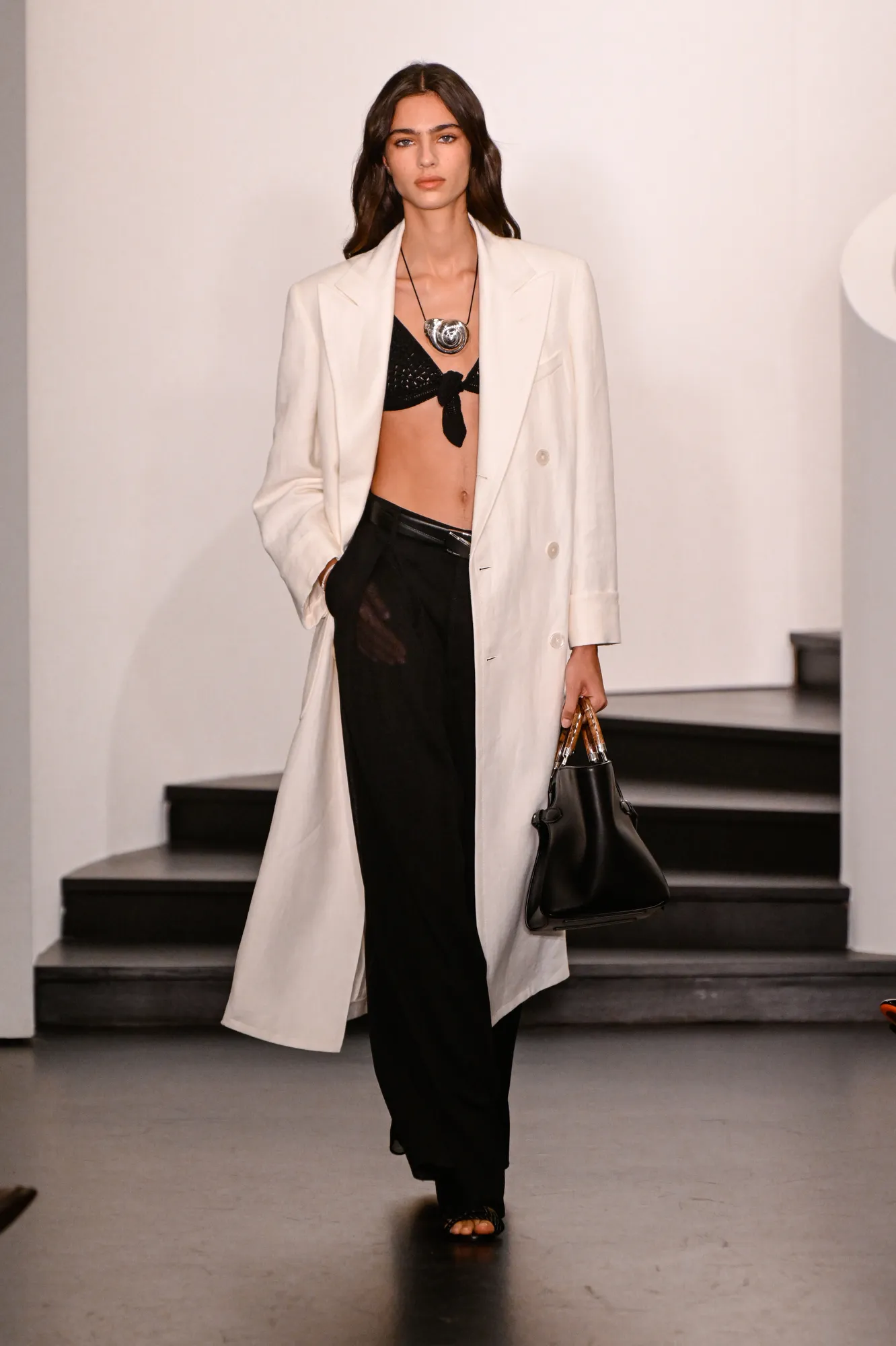 Ralph Lauren Spring 2026 monochrome runway look Ralph Lauren Spring 2026 monochrome look with black bra, white coat and black trousers at New York Fashion Week
