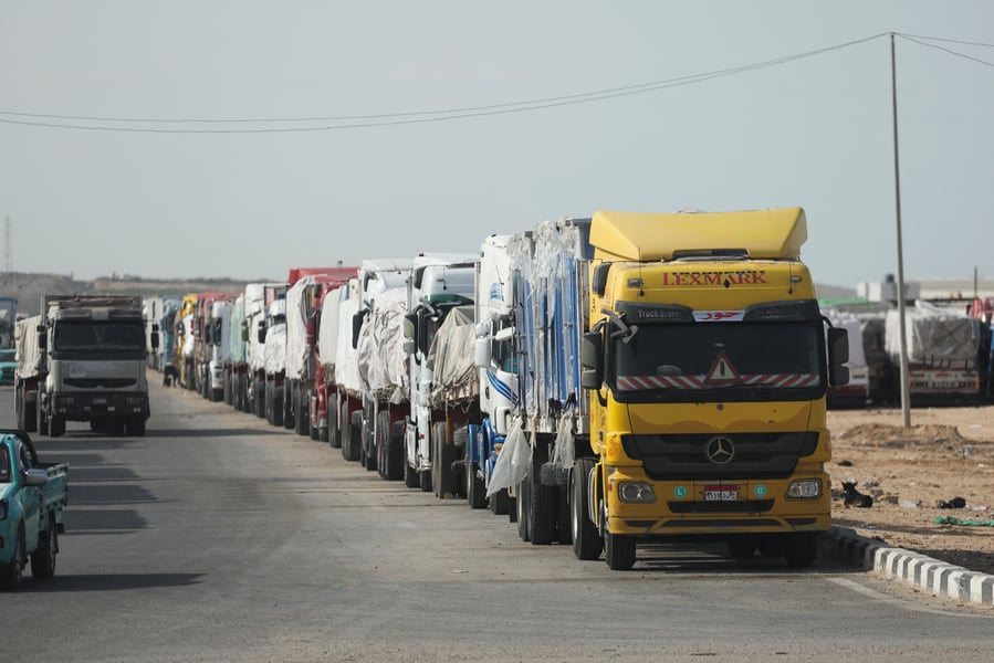 Rows of humanitarian aid trucks at Kerem Shalom crossing as inspections slow throughput.