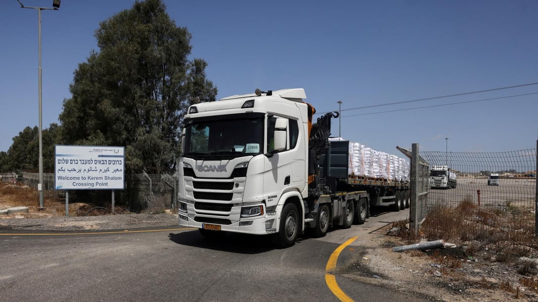 Border inspection lanes with posted hours and signage as trucks line up for checks