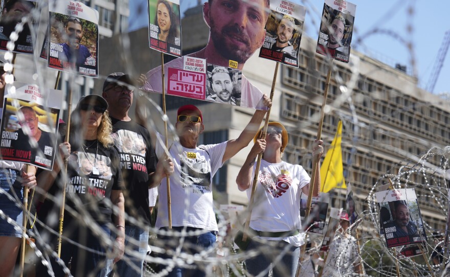Families at Tel Aviv’s Hostages Square hold photos and candles during the ceasefire