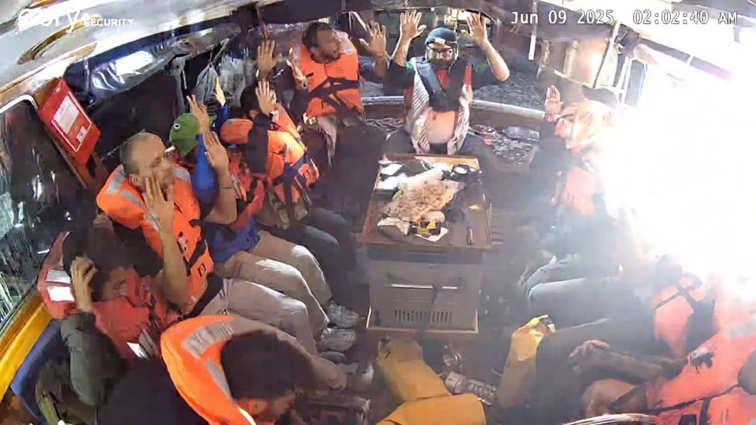 Passengers in life vests stand on deck as boarding teams approach during the flotilla interception.
