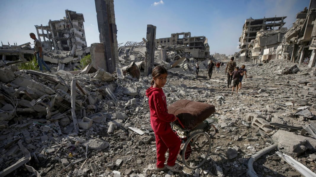 Residents walk past collapsed apartment blocks in the Zeitoun area of Gaza City