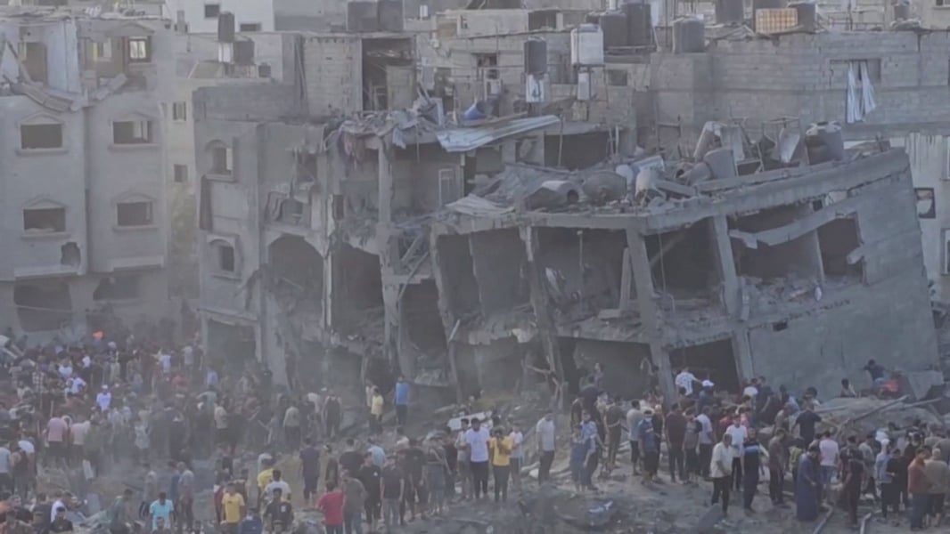 People walk through a devastated street in Jabalia as aid schedules fluctuate